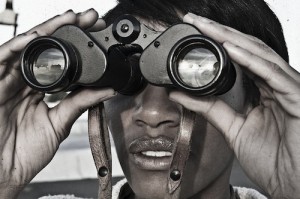 Close-up photo of person looking through binoculars.