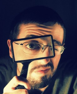 man with glasses peering through a rectangular magnifying glass