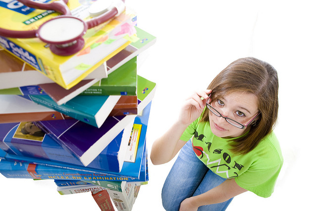 girl with glasses beside a huge pile of books