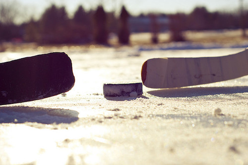 close up of hockey blades and puck on a frozen pond